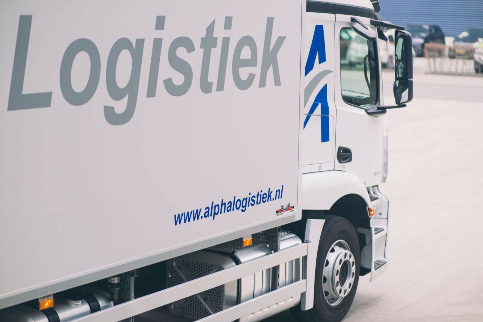 Zijkant Alpha Logistiek vrachtwagen, met het logo zichtbaar